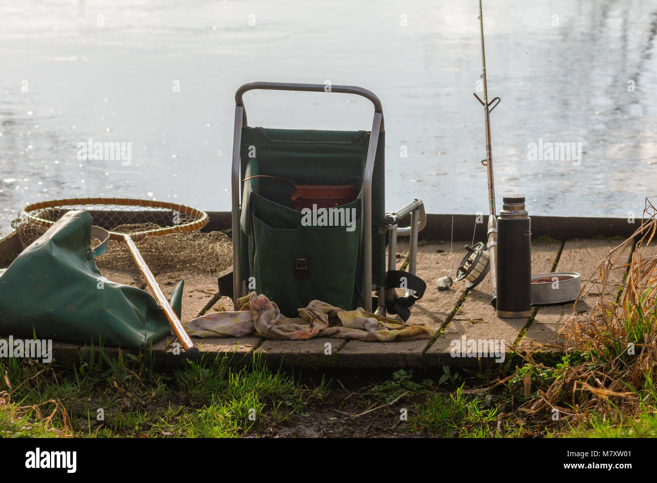 Un tranquillo Fisherman's Fishing Tackle lasciati incustoditi su un argine stazione di pesca. Foto Stock