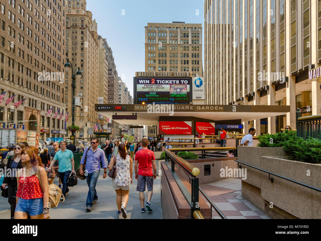 Le persone che camminano lungo la 7th Avenue oltrepassano il Madison Square Garden, un'arena polivalente al coperto nel centro di Manhattan, New York City Foto Stock