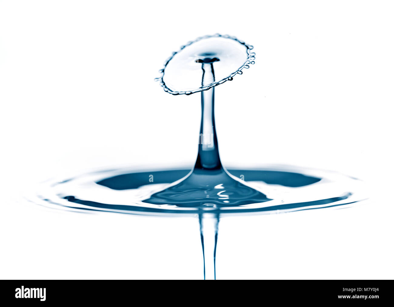 Splash e corona su increspato azzurro liquido o superficie di acqua . Spruzzi di acqua con una corona e di riflessione Foto Stock