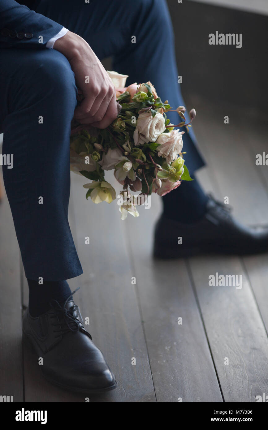 Elegante groom tenendo una gara rosa bouquet di nozze Foto Stock