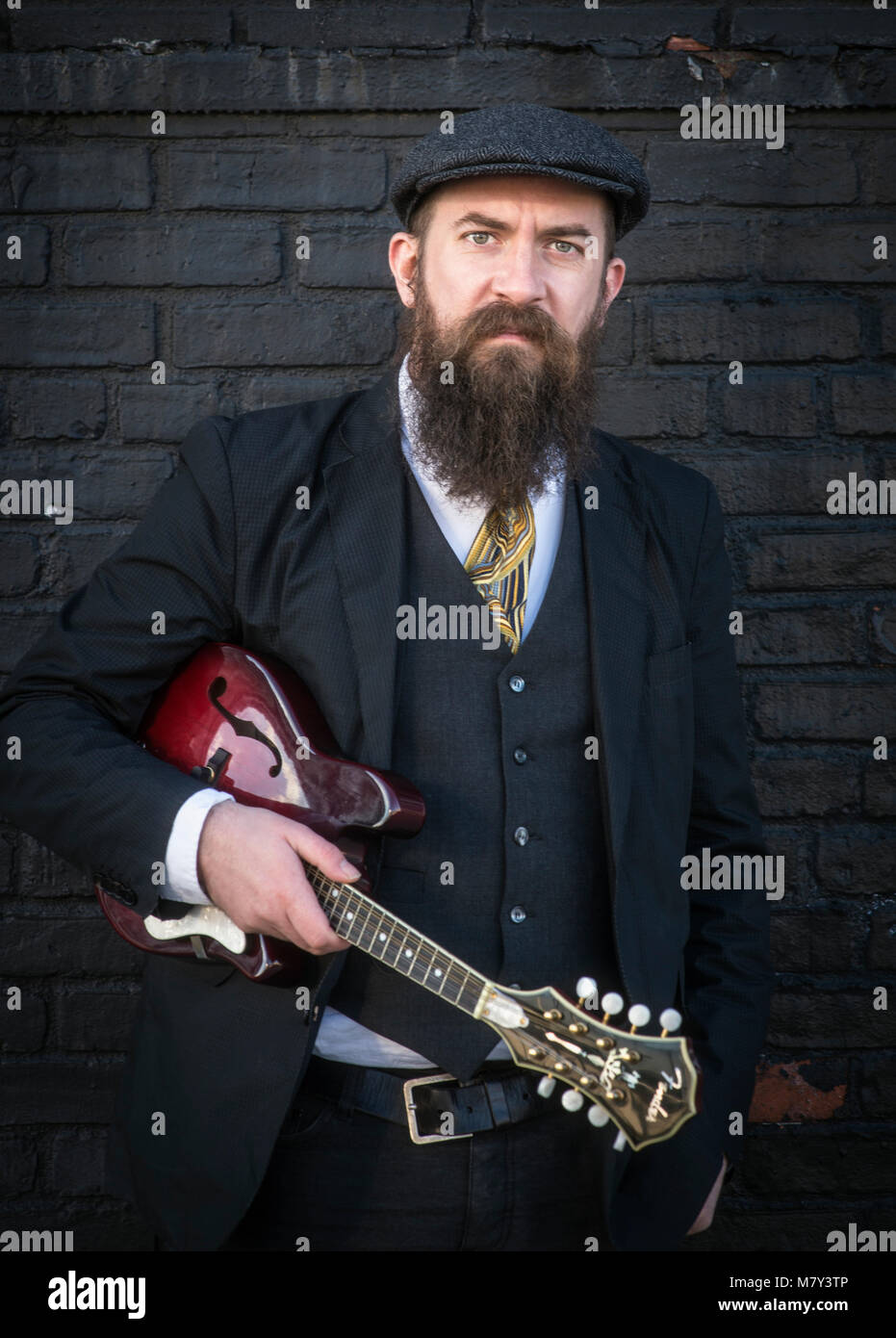Un uomo barbuto in piedi con un mandolino. Foto Stock