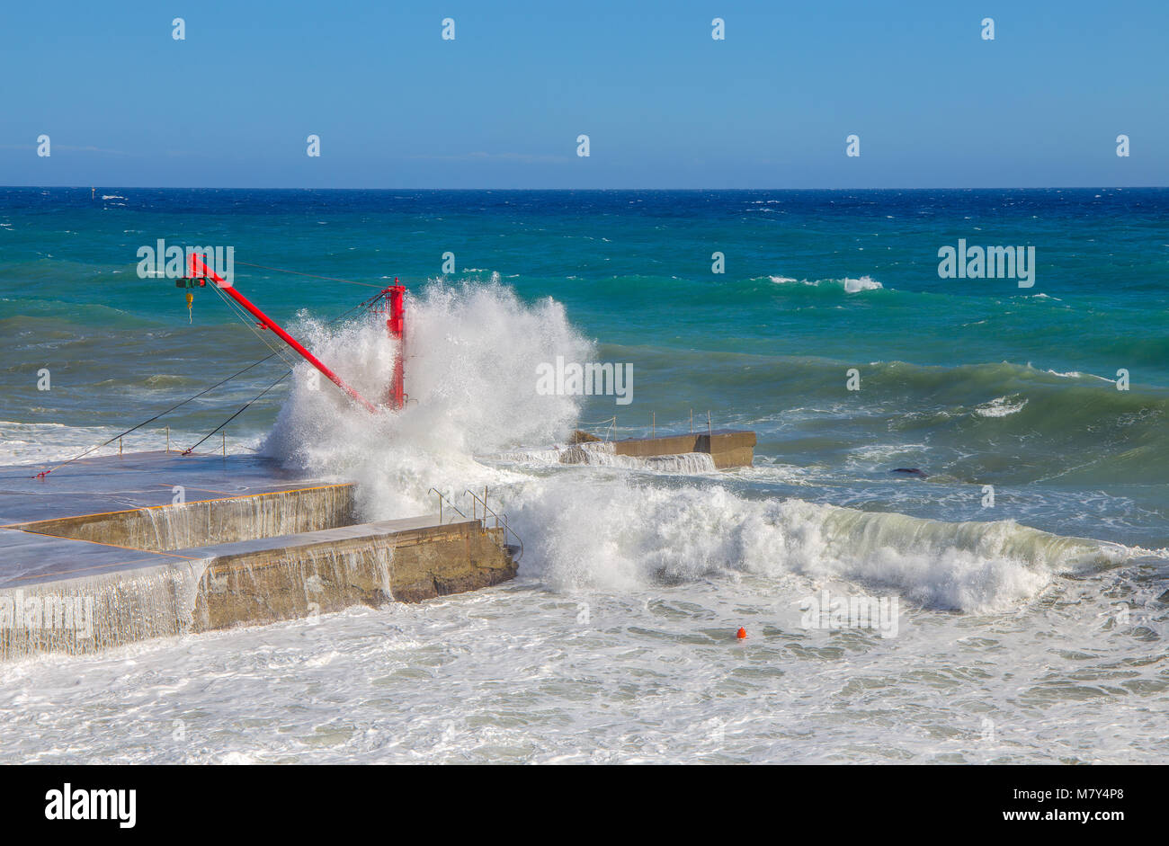 La gru rosso sul molo con mare mosso Foto Stock