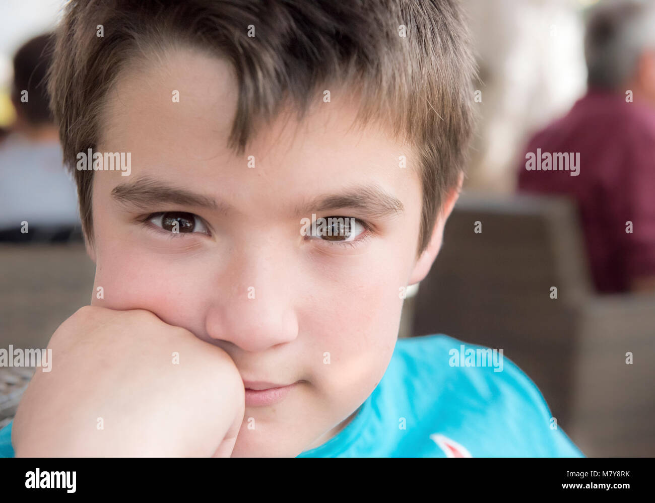 Bambino marrone con occhi spalancati,marrone capelli e la mano nel suo volto alla ricerca di noi Foto Stock
