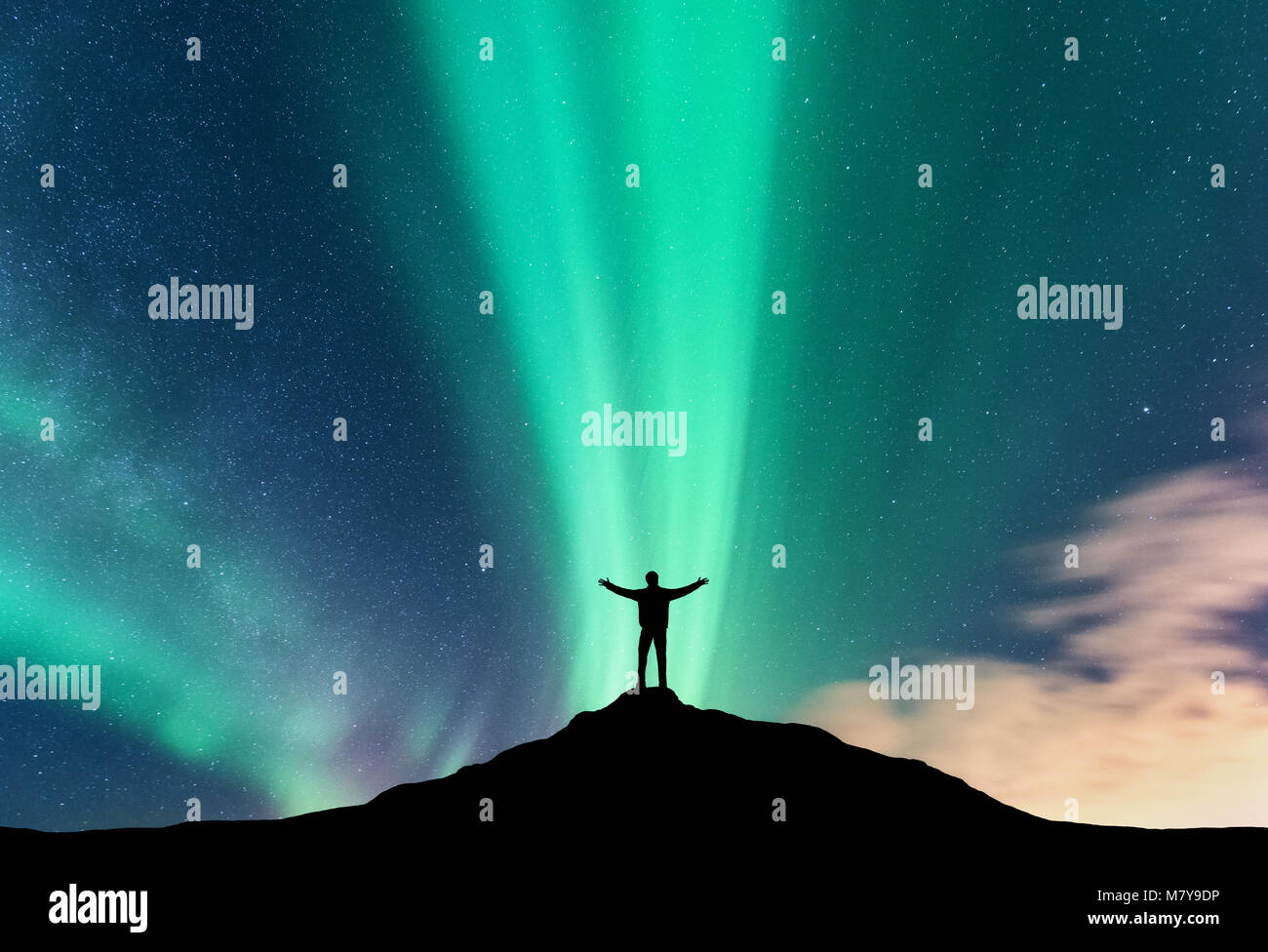 Aurora e la silhouette di un uomo in piedi con sollevata bracci sulla montagna. Isole Lofoten in Norvegia. Aurora boreale e uomo felice. Cielo con le stelle e Foto Stock