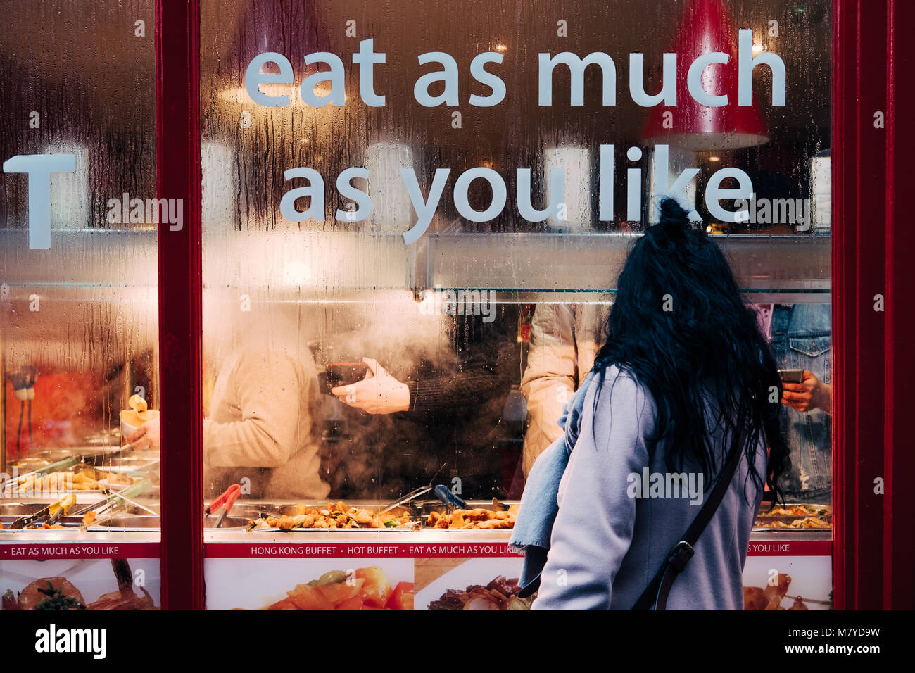 Donna che guarda al suo interno attraverso il vetro di cinesi Buffet caldo in Chinatown. Foto Stock