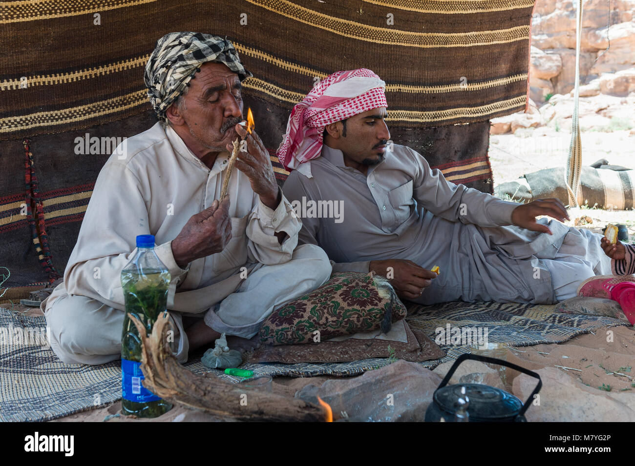 Due uomini di fumare una sigaret e rilassante nella loro tenda beduina nel Wadi Rum in Giordania. Foto Stock