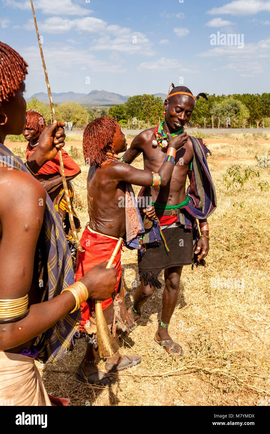 Giovani donne Hamar Taunt A Hamar Tribesman alla fustigazione essi durante un 'proveniente dall'età' Bull Jumping cerimonia, Dimeka, Valle dell'Omo, Etiopia Foto Stock