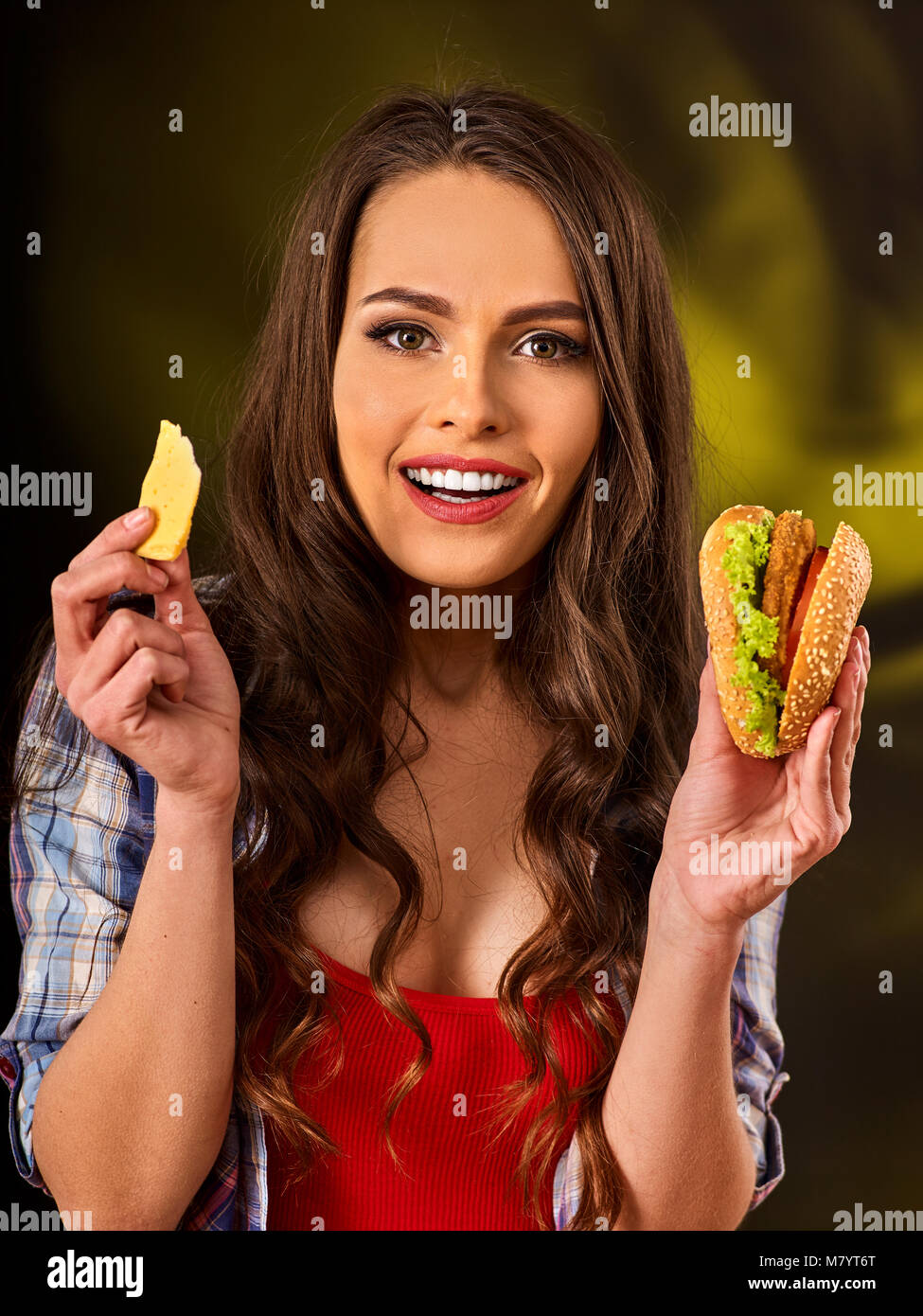 Donna di mangiare patatine e hamburger sul tavolo. Foto Stock