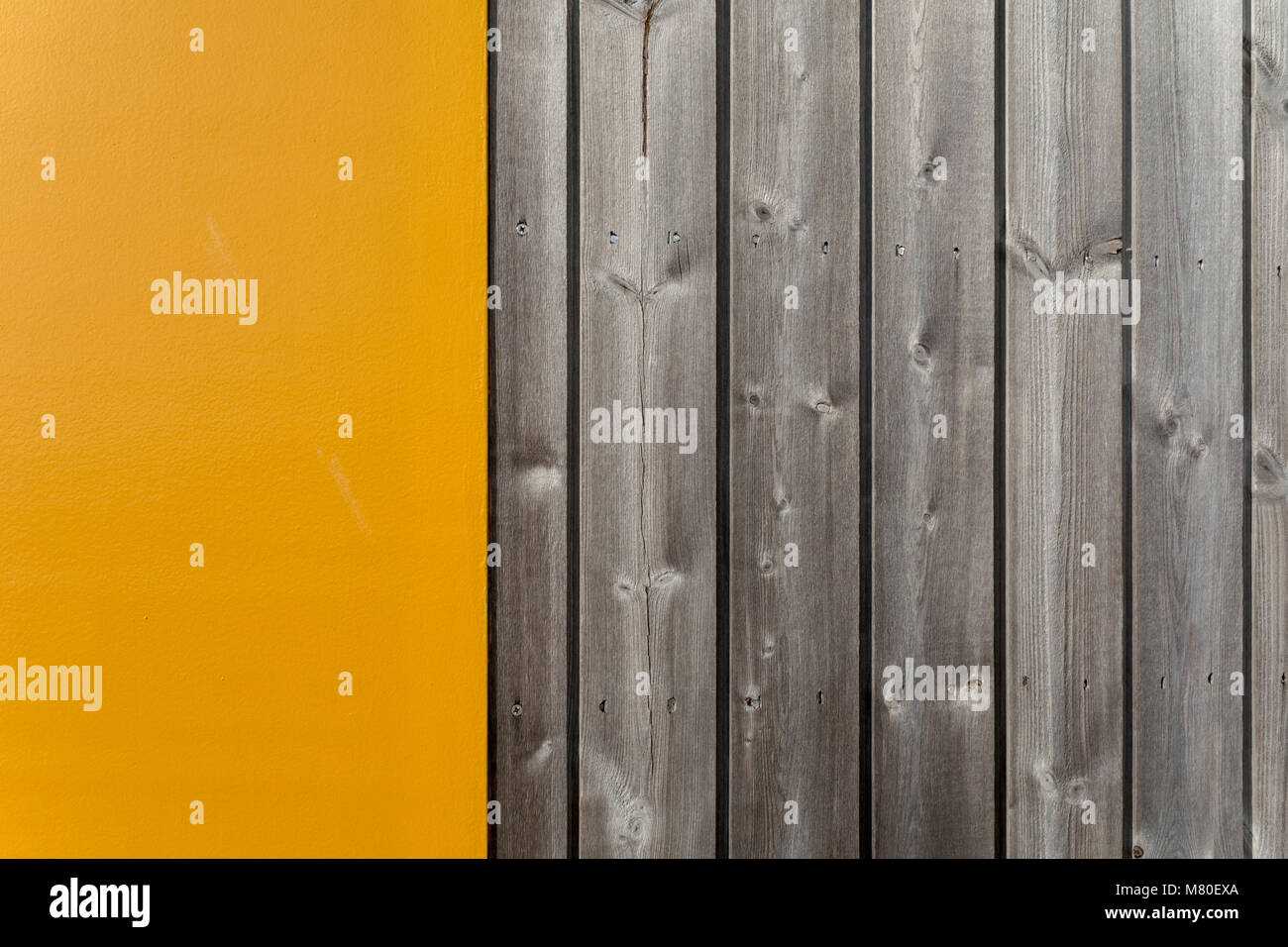 Verniciato giallo sezione accanto al grigio verticale di tavole di legno su una spiaggia rifugio a Bexhill-on-Sea Foto Stock