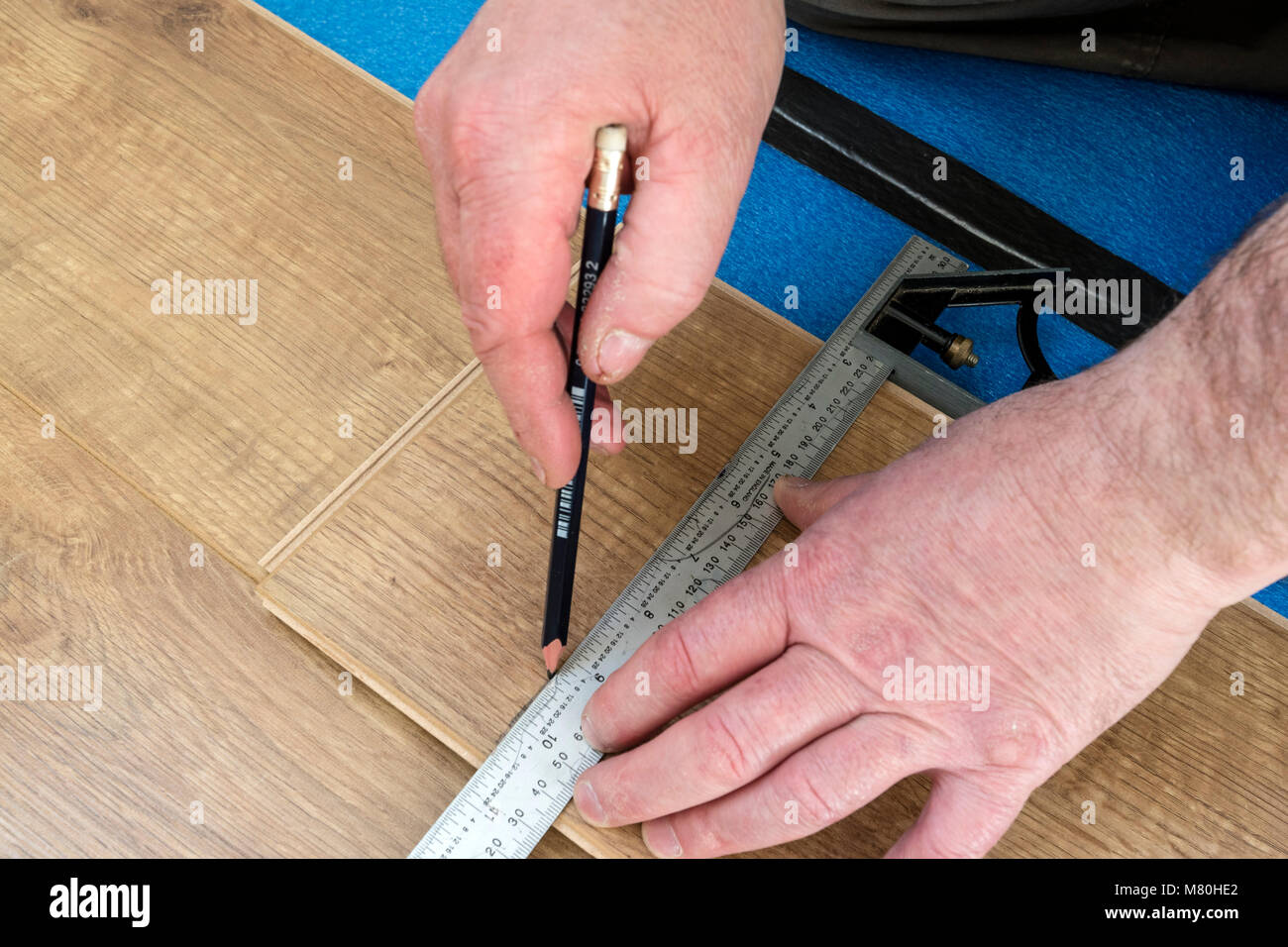 Una persona di marcatura di un pavimento laminato bordo pronti per il taglio utilizzando un set di combinazione Square, Regno Unito. Foto Stock