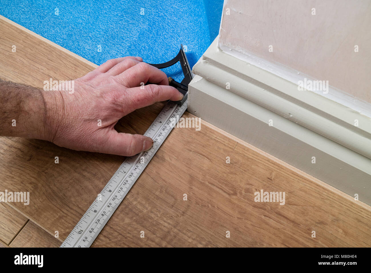 Una persona di marcatura di un pavimento laminato Board utilizzando un set di combinazione quadrata per contrassegnare un angolo, UK. Foto Stock