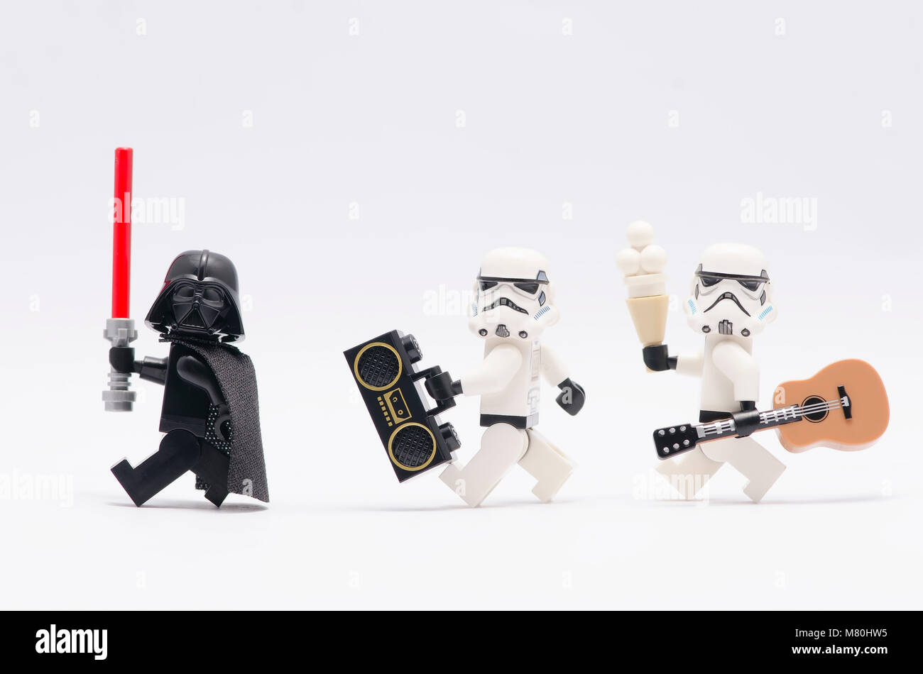 Lego Darth Vader azienda light saber con storm troopers tenendo un radio e una chitarra. isolato su sfondo bianco. Foto Stock