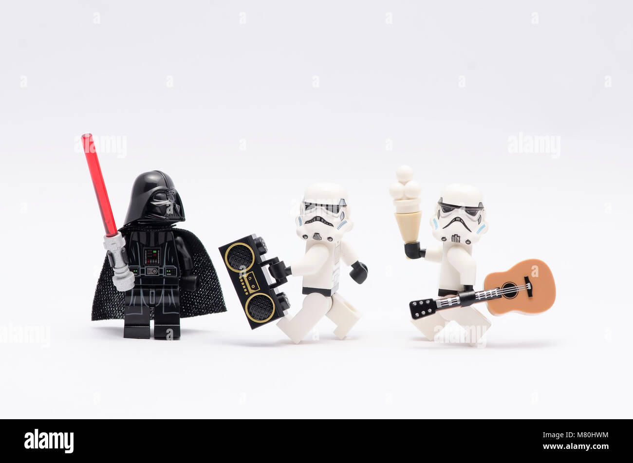 Lego Darth Vader azienda light saber guardando storm troopers tenendo un radio e una chitarra. isolato su sfondo bianco. Foto Stock