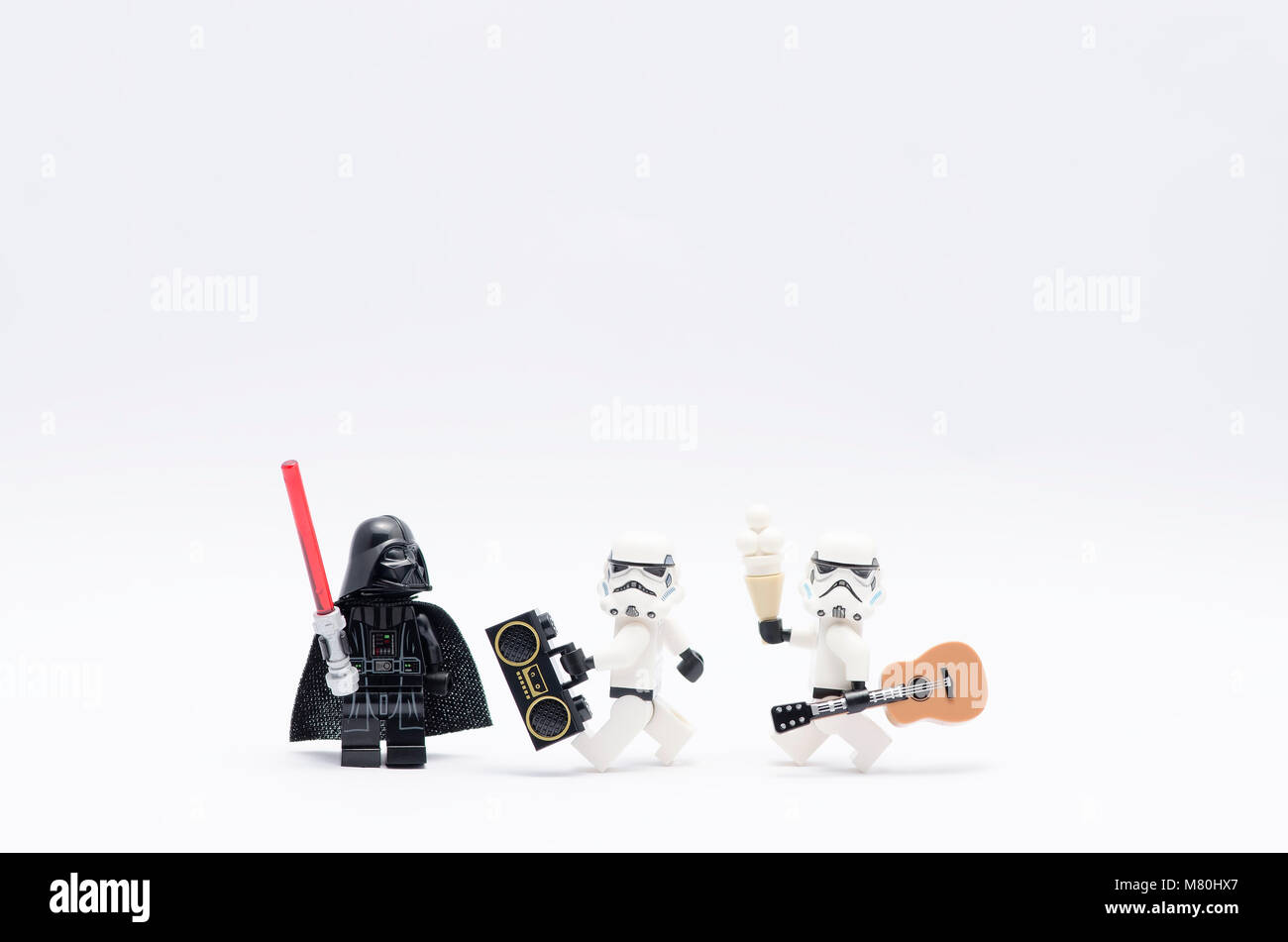 Lego Darth Vader azienda light saber guardando storm troopers tenendo un radio e una chitarra. isolato su sfondo bianco. Foto Stock