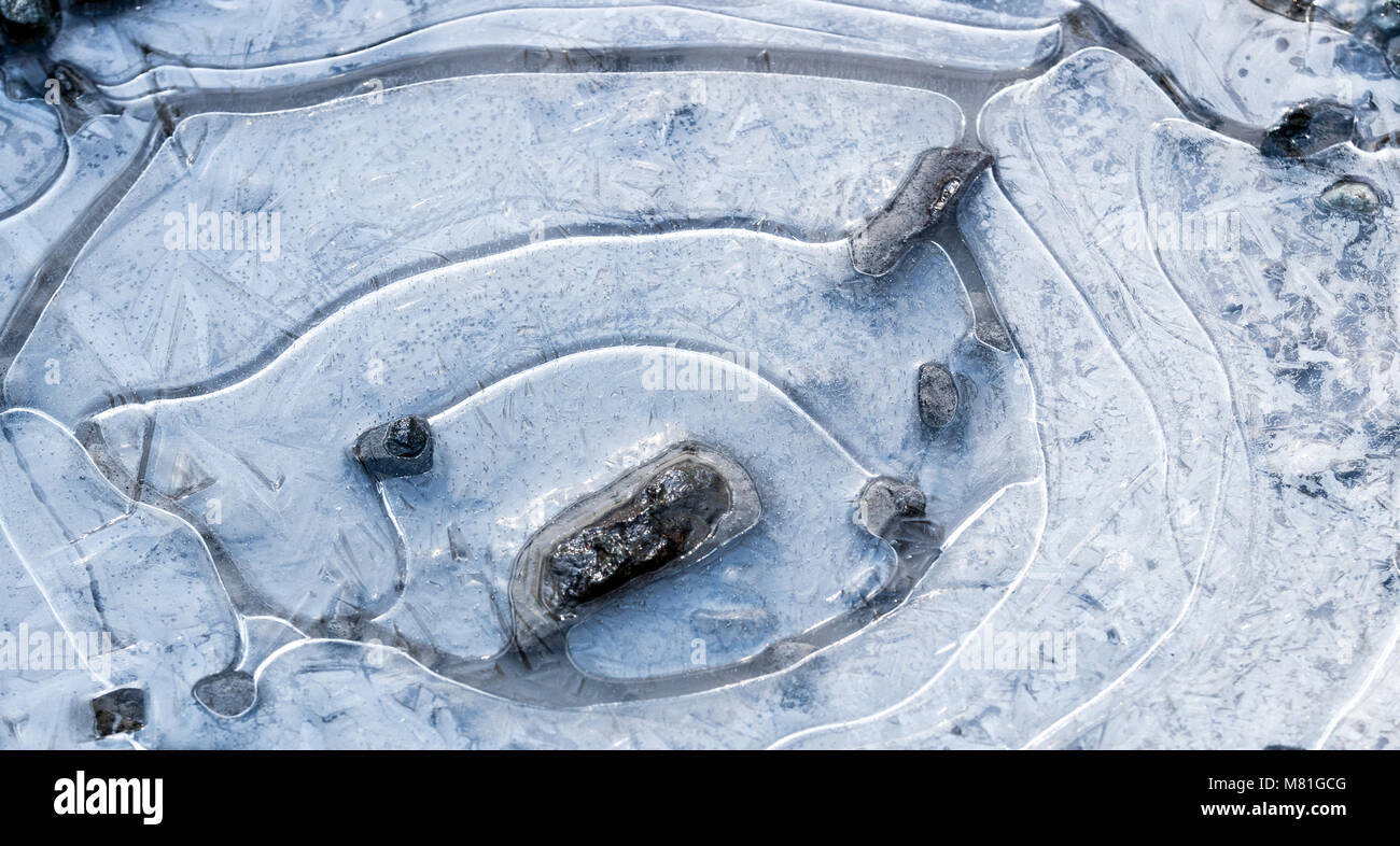 Pozza di fango ghiacciato con il bianco dei cristalli di ghiaccio, anelli di aria, rocce e visibile Foto Stock