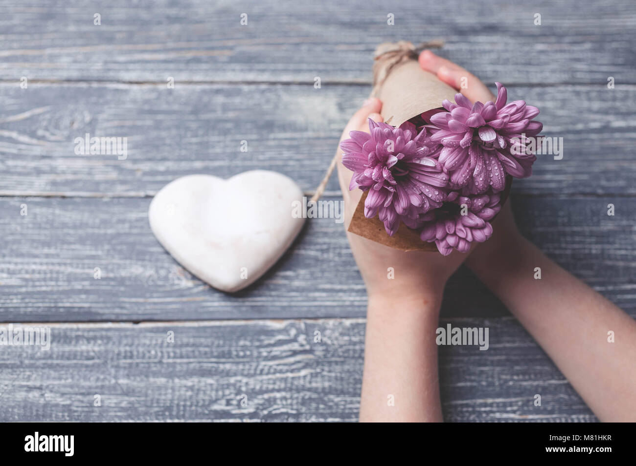 I bambini con le mani in mano tenere biscotti a forma di cuore su di un piano in legno. Concept del Giorno della Madre. Tonificante morbido. Foto Stock