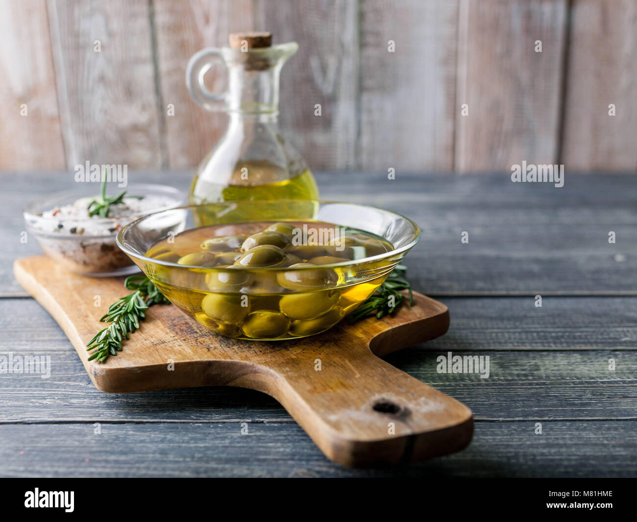 Olio d'oliva nella Contessa e olive con spezie e erbe fragranti su uno sfondo di legno. Foto Stock