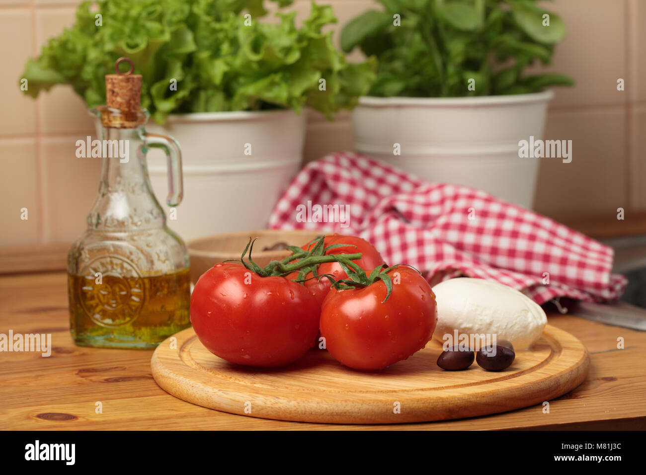 Pomodori, mozzarella, olive kalamata e olio di oliva su un tavolo in una cucina domestica Foto Stock