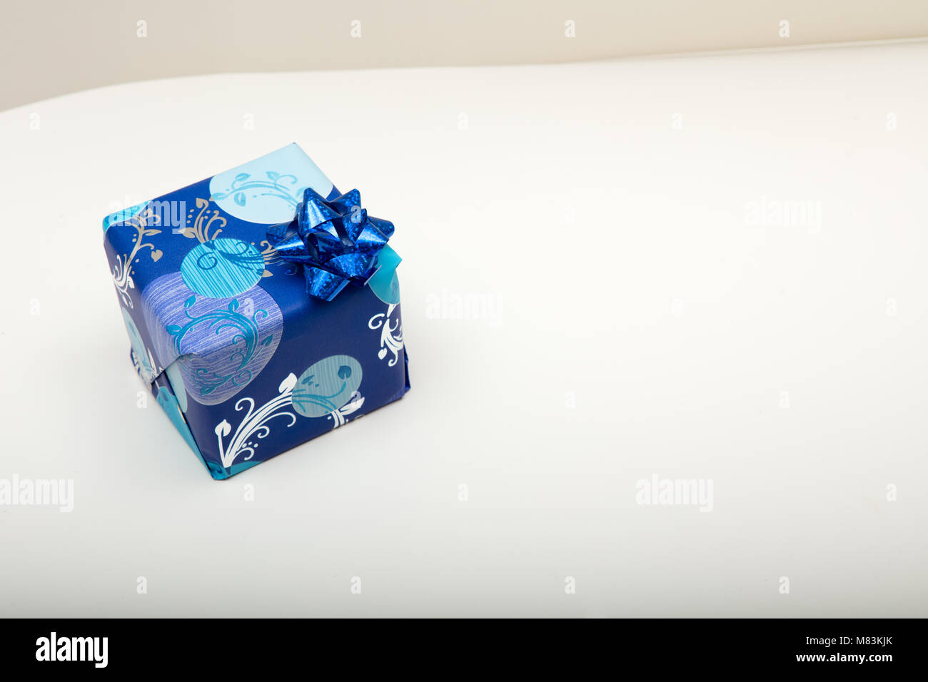 Confezione regalo avvolto in decorativi carta blu con una lamina metallica  nastro bow visto elevato angolo su bianco con spazio di copia Foto stock -  Alamy