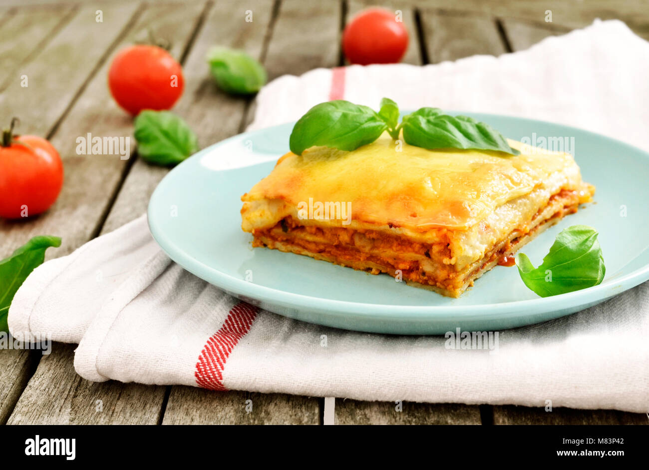 Carni fresche lasagne, lasagne alla bolognese, piatto di pasta su una tavola di legno con una decorazione foglia di basilico. Cucina Italiana. Foto Stock