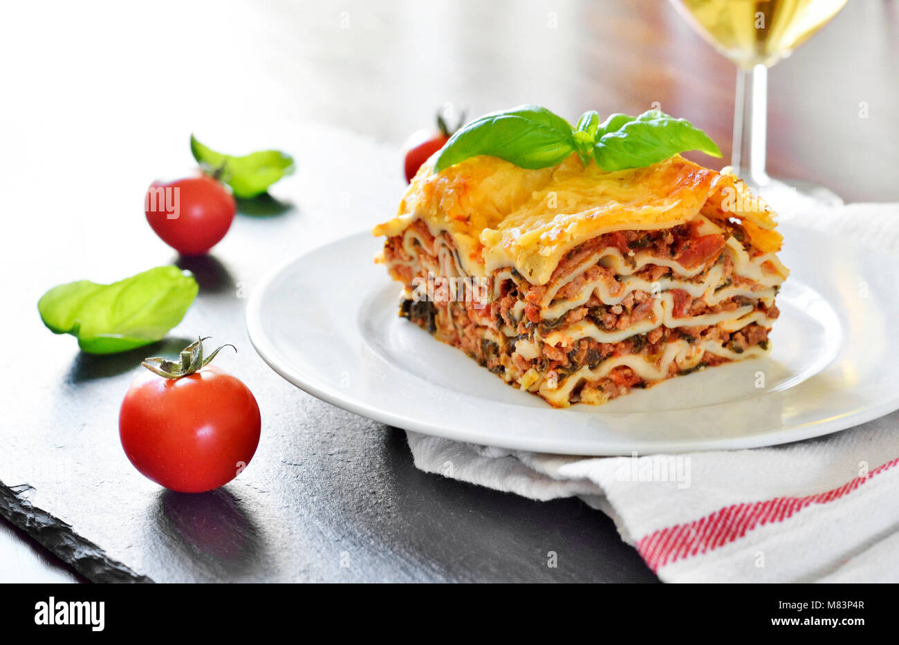Carni fresche lasagne, lasagne alla bolognese, piatto di pasta su una tavola di legno con una decorazione foglia di basilico. Cucina Italiana. Foto Stock