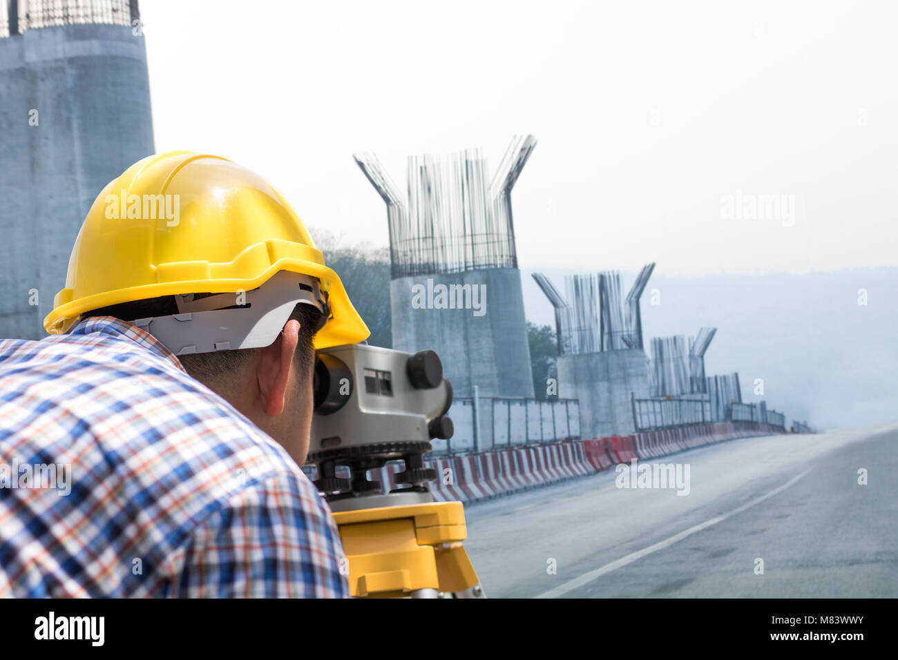 Ingegnere e lavoratore cerca a livello di strumento di misura sulla strada e ponte di costruzione Foto Stock