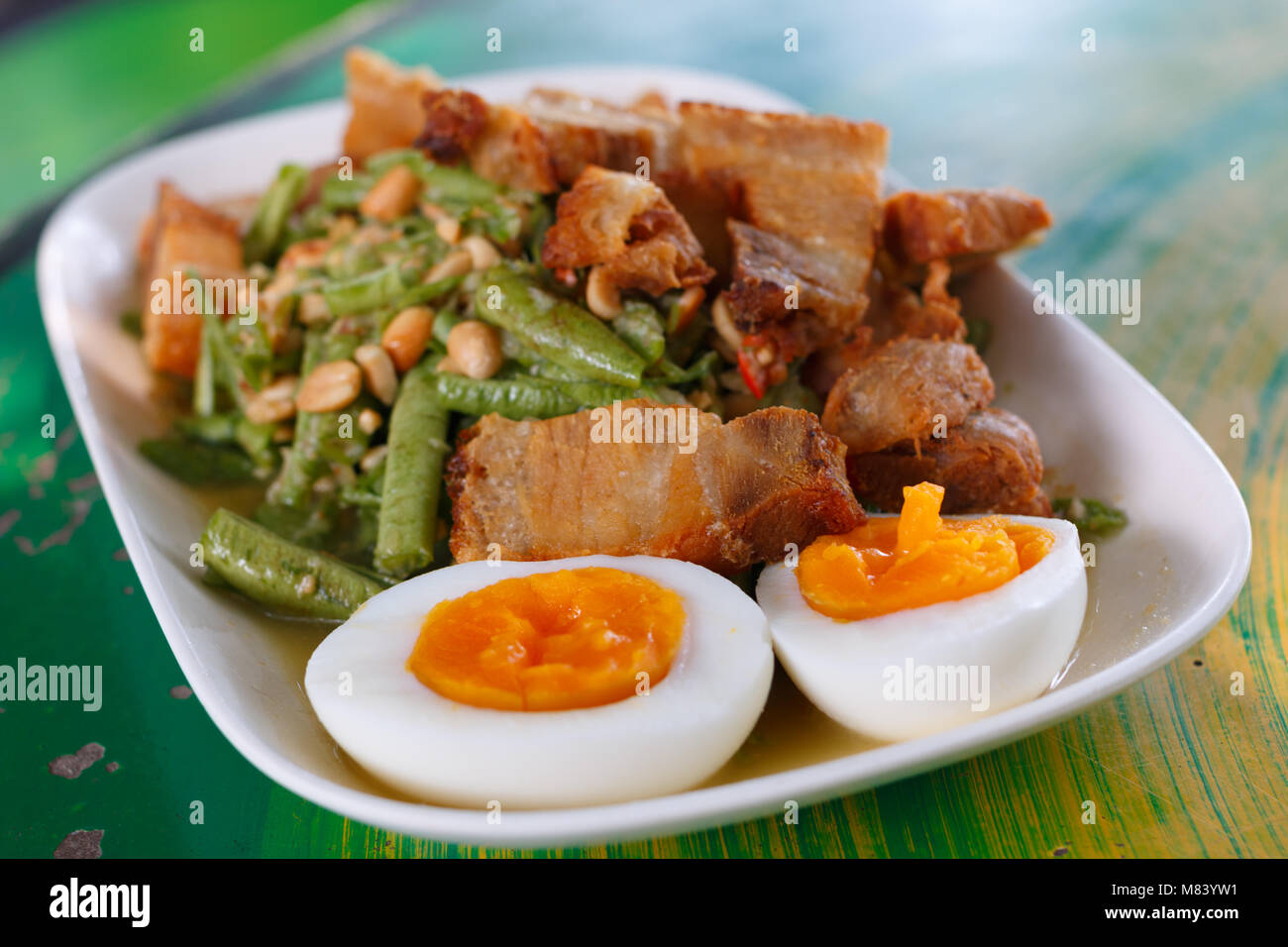 Fette di carne di maiale croccante e uovo sodo su Yardlong insalata di fagioli tradizionale cibo tailandese Foto Stock