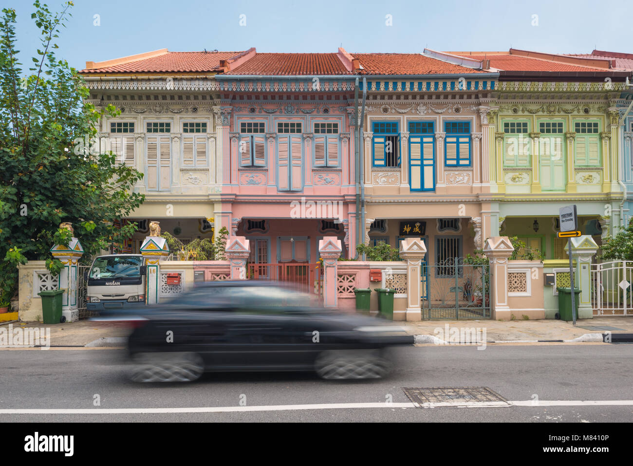 Negozio di patrimonio case lungo Joo Chiat Road. Una moderna autovettura con motion blur è all'avanguardia. Foto Stock