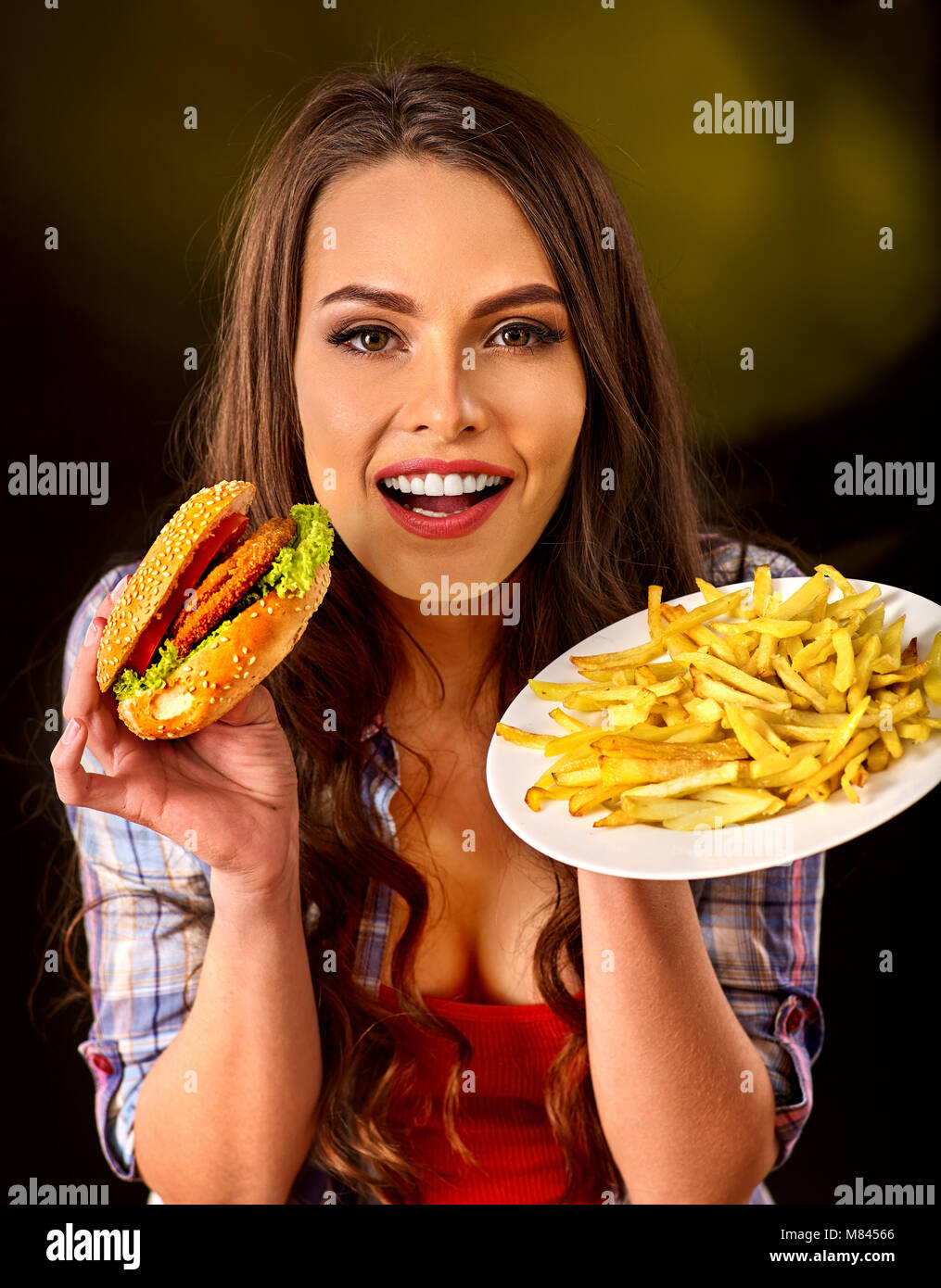 Donna di mangiare patatine e hamburger sul tavolo. Foto Stock