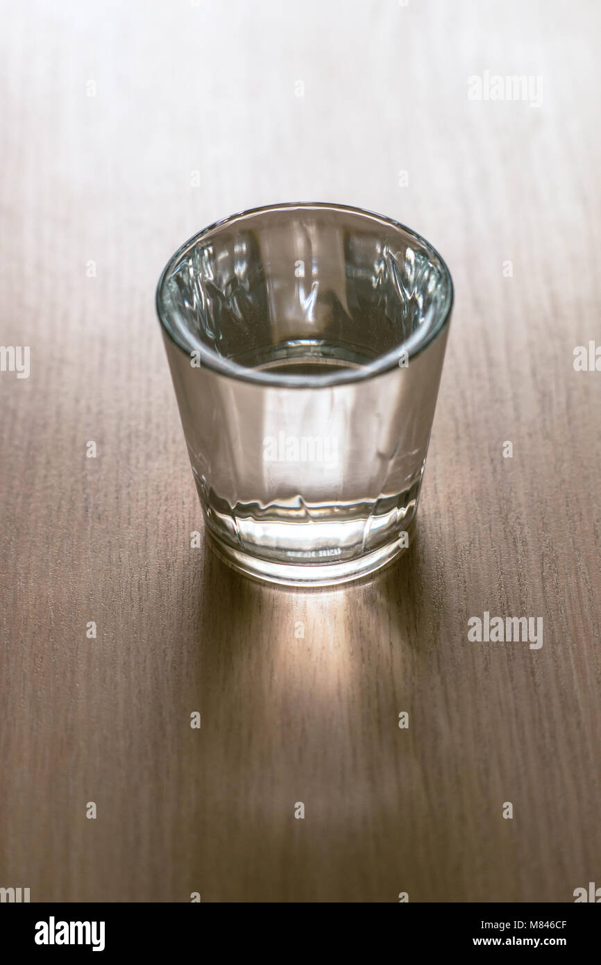 Vetro sfaccettate di acqua su un tavolo di legno Foto Stock