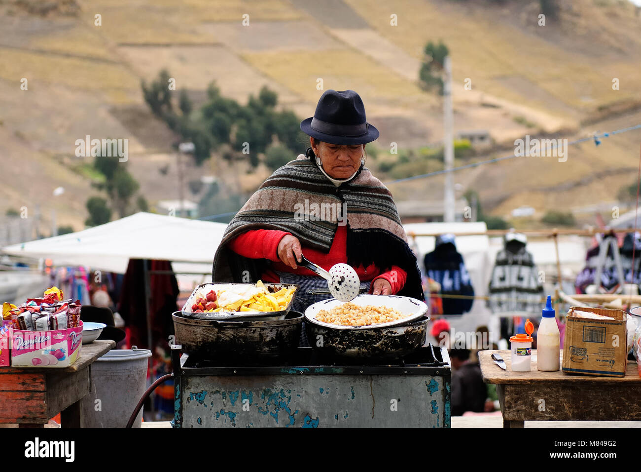 ECUADOR, PUJILI - 11 agosto 2012; ecuadoriana donna etnica in vestiti nazionali di vendita di alimenti altri alimenti su un mercato nel villaggio di Pujili Foto Stock