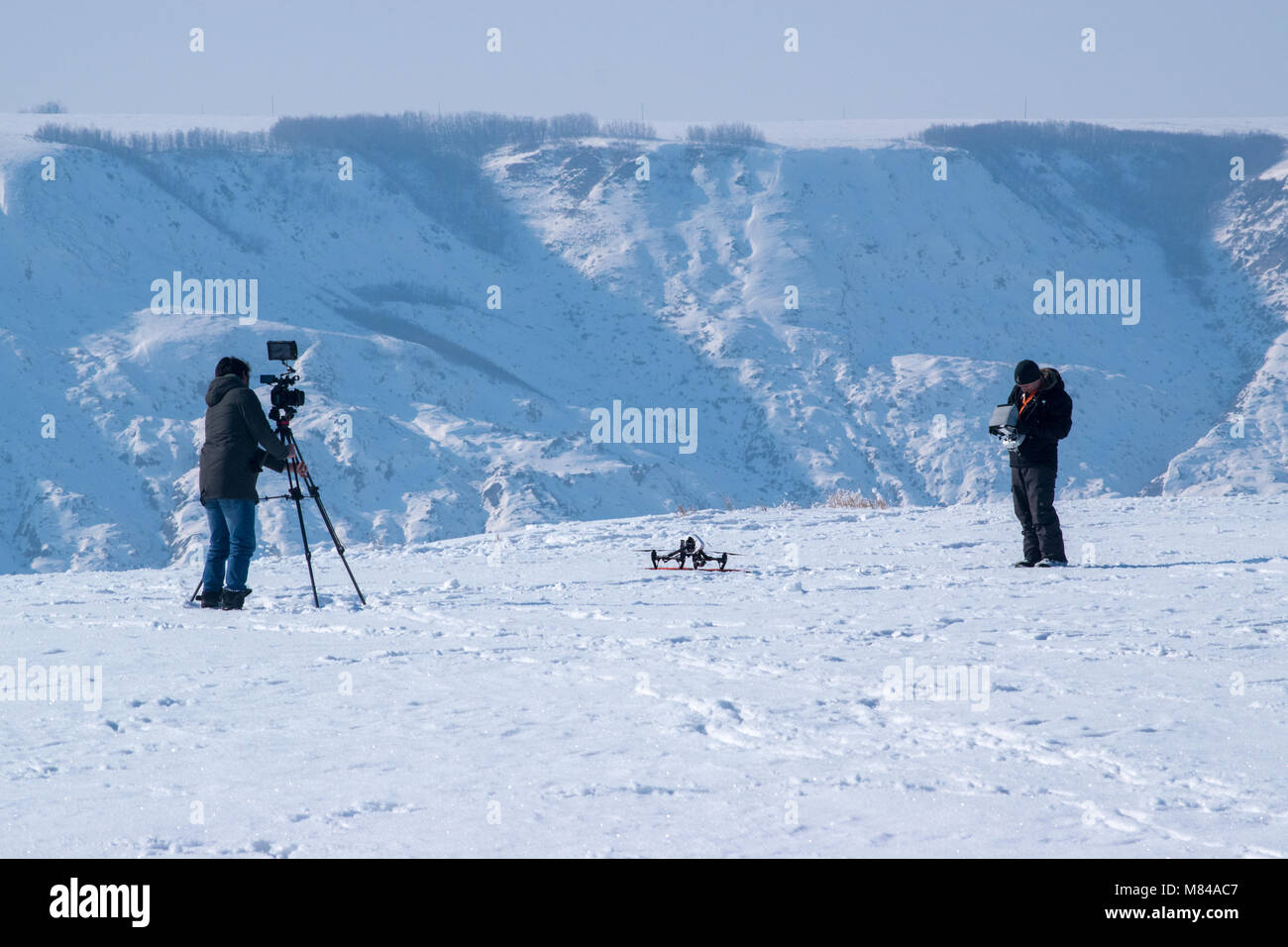 Un uomo della fotocamera pellicole un operatore drone a preparare il lancio vicino Horsethief canyon a nord di Drumheller, Alberta. Il funzionamento di un drone in Canada è disciplinata b Foto Stock