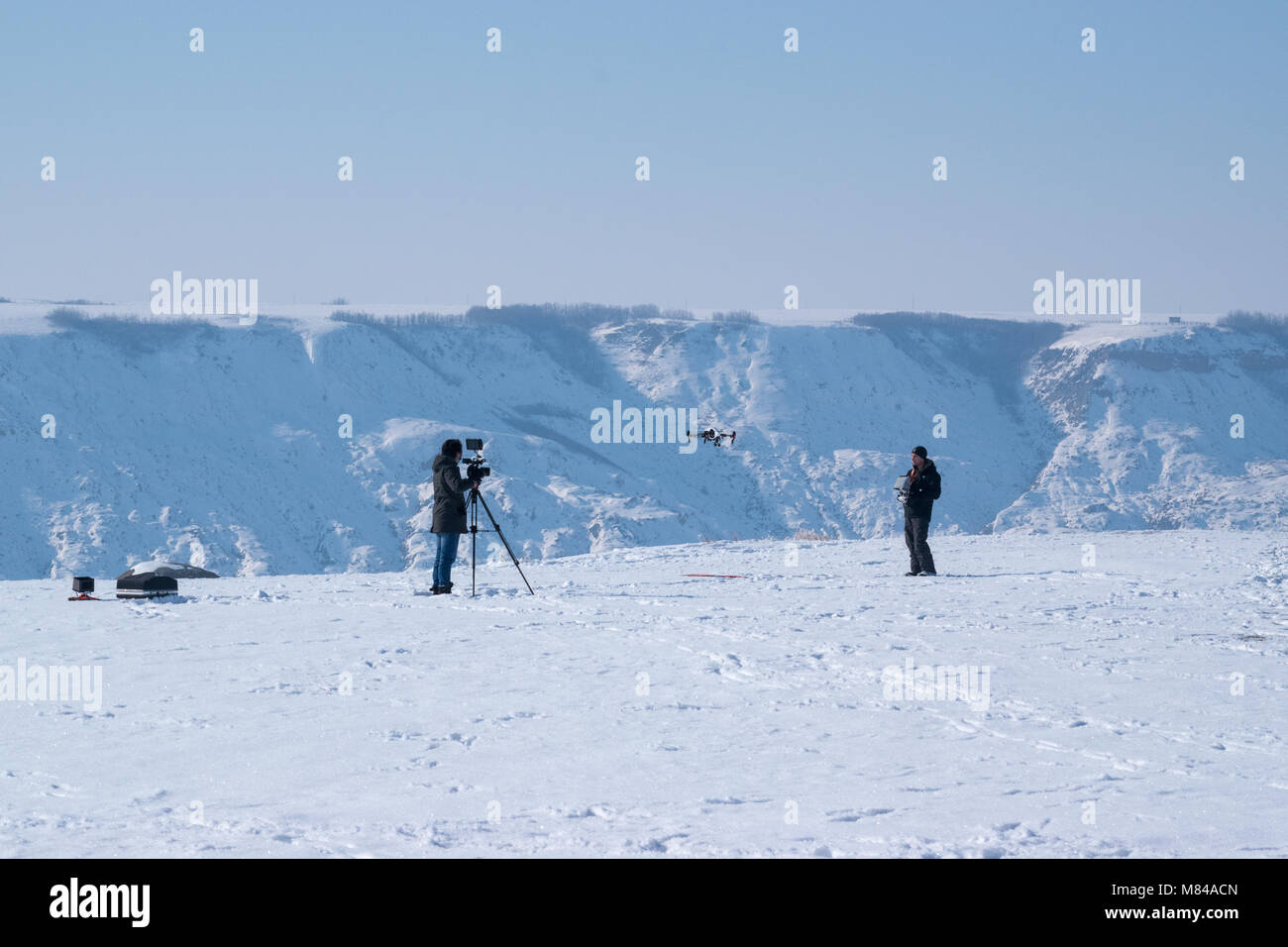 Un uomo della fotocamera pellicole un operatore drone a preparare il lancio vicino Horsethief canyon a nord di Drumheller, Alberta. Il funzionamento di un drone in Canada è disciplinata b Foto Stock