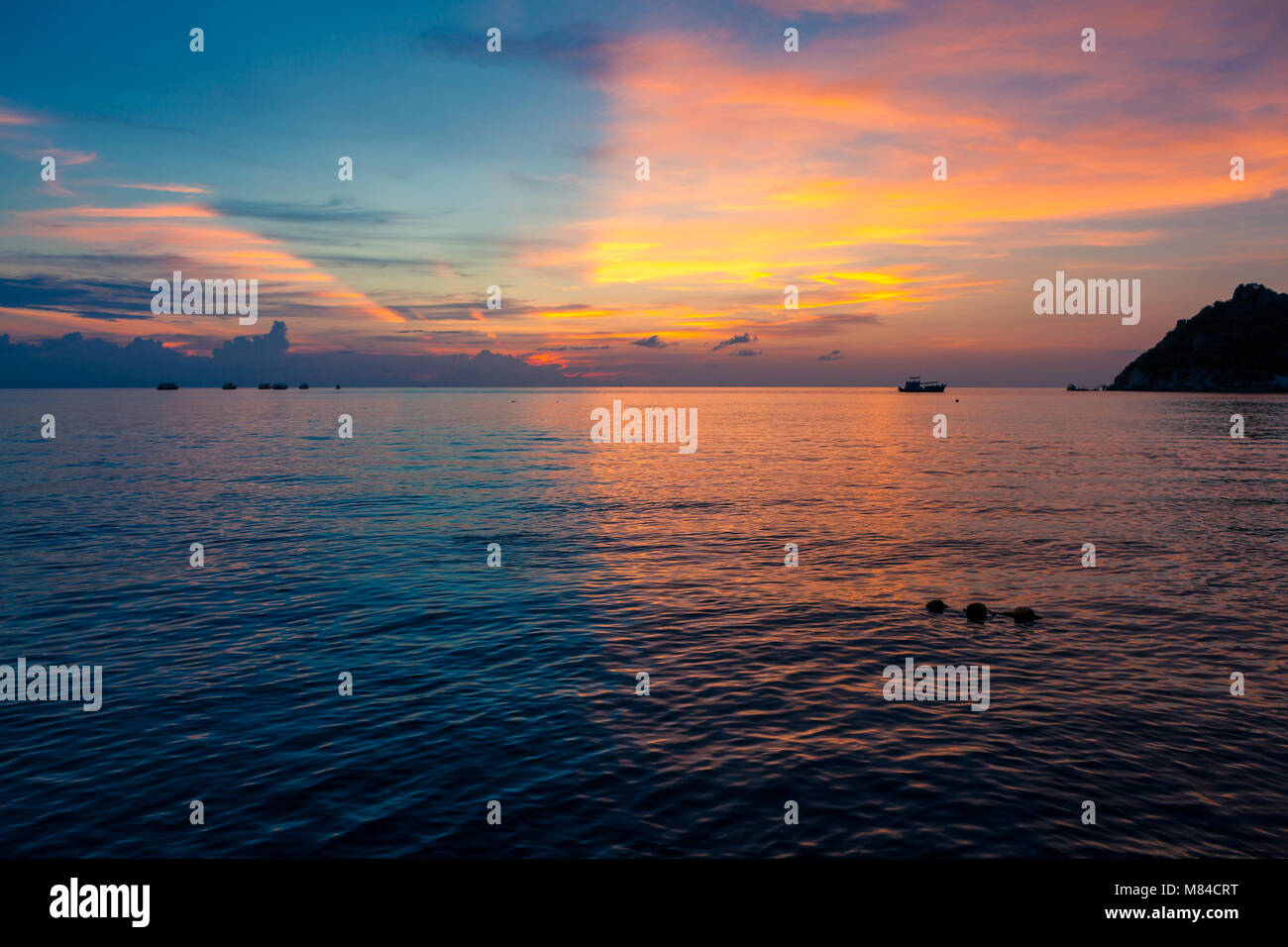 Incredibile tramonto con metà blu e metà giallo arancione e rosa cielo sopra il mare. Vista dell'Isola Nang Yuan da Ko Tao, con buoyants nell'acqua Foto Stock
