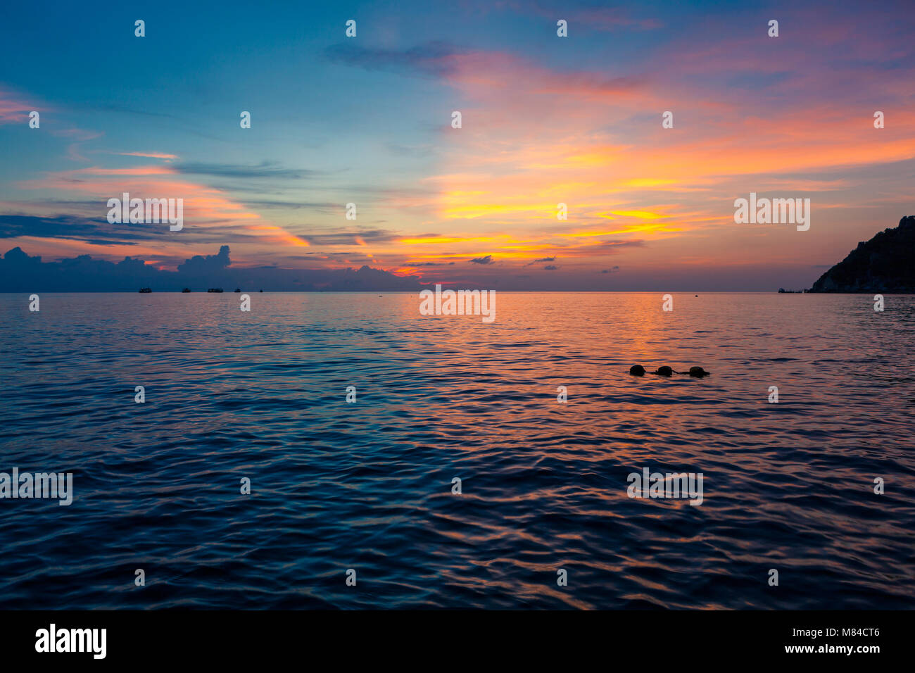 Incredibile tramonto con metà blu e metà giallo arancione e rosa cielo sopra il mare. Vista dell'Isola Nang Yuan da Ko Tao, con buoyants nell'acqua Foto Stock