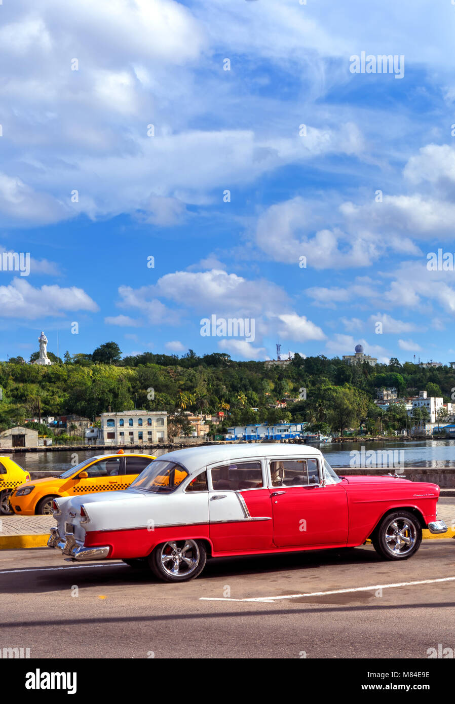 Il bianco e il rosso brillante classico auto nel centro di Havana Cuba con la statua di Gesù in background Foto Stock