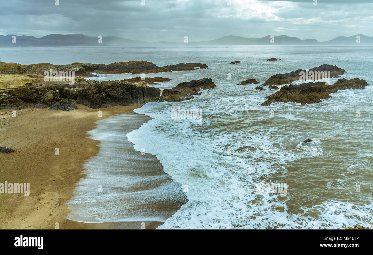 Regno Unito, Anglesey, Newborough, 11 marzo 2018. Onde che si infrangono sulla punta di Llanddwyn Island. Foto Stock