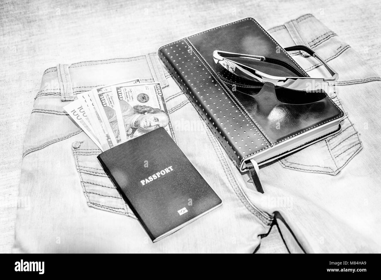 Passaporto con denaro bollette, bicchieri e notepad giacciono su jeans. Il concetto di viaggio. Foto Stock