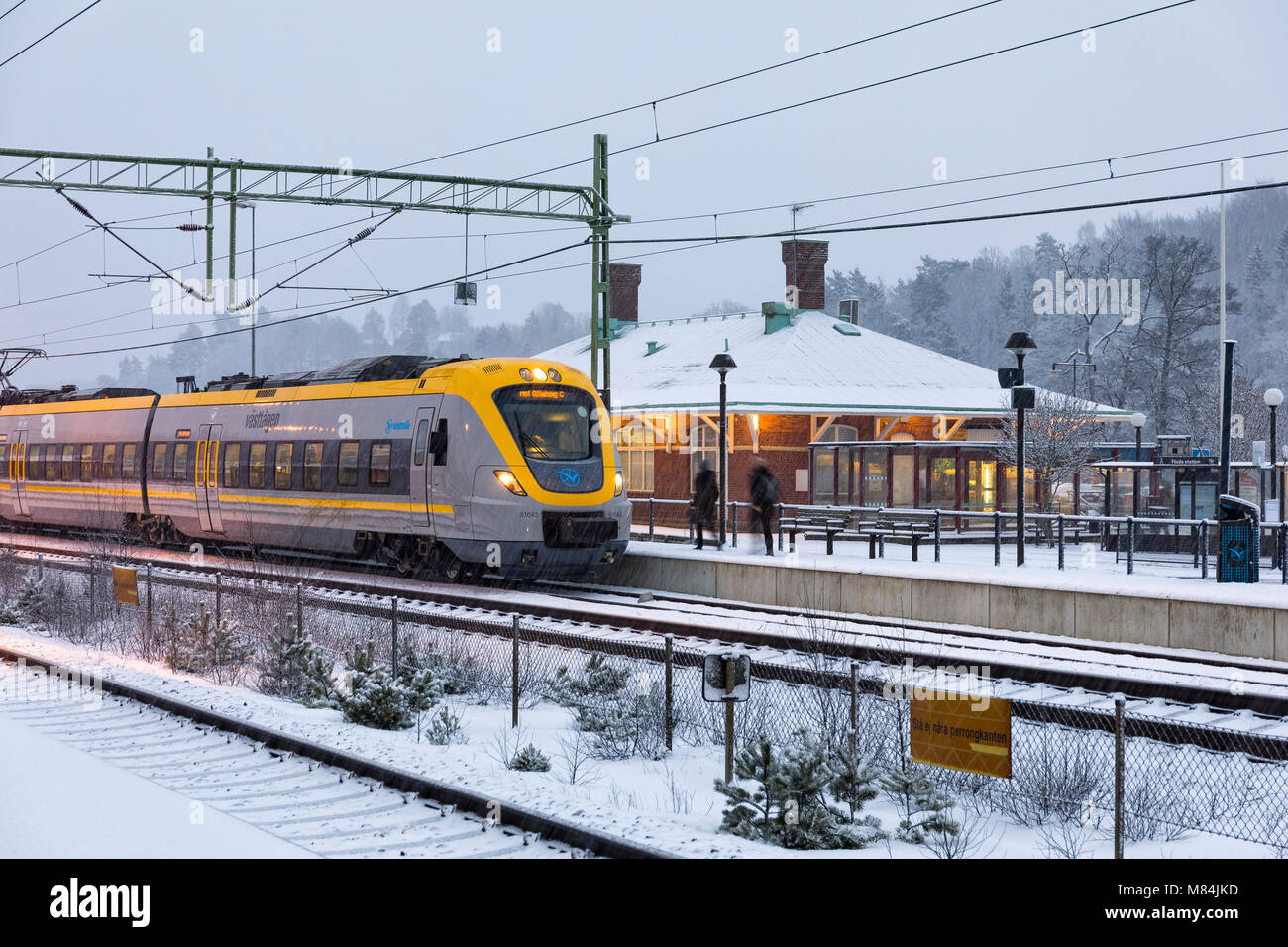 FLODA, Svezia - 16 febbraio: Moderna commuter rail treno passeggeri o ferrovia suburbana a stazione ferroviaria di neve durante l'inverno modello di rilascio: No. Proprietà di rilascio: No. Foto Stock