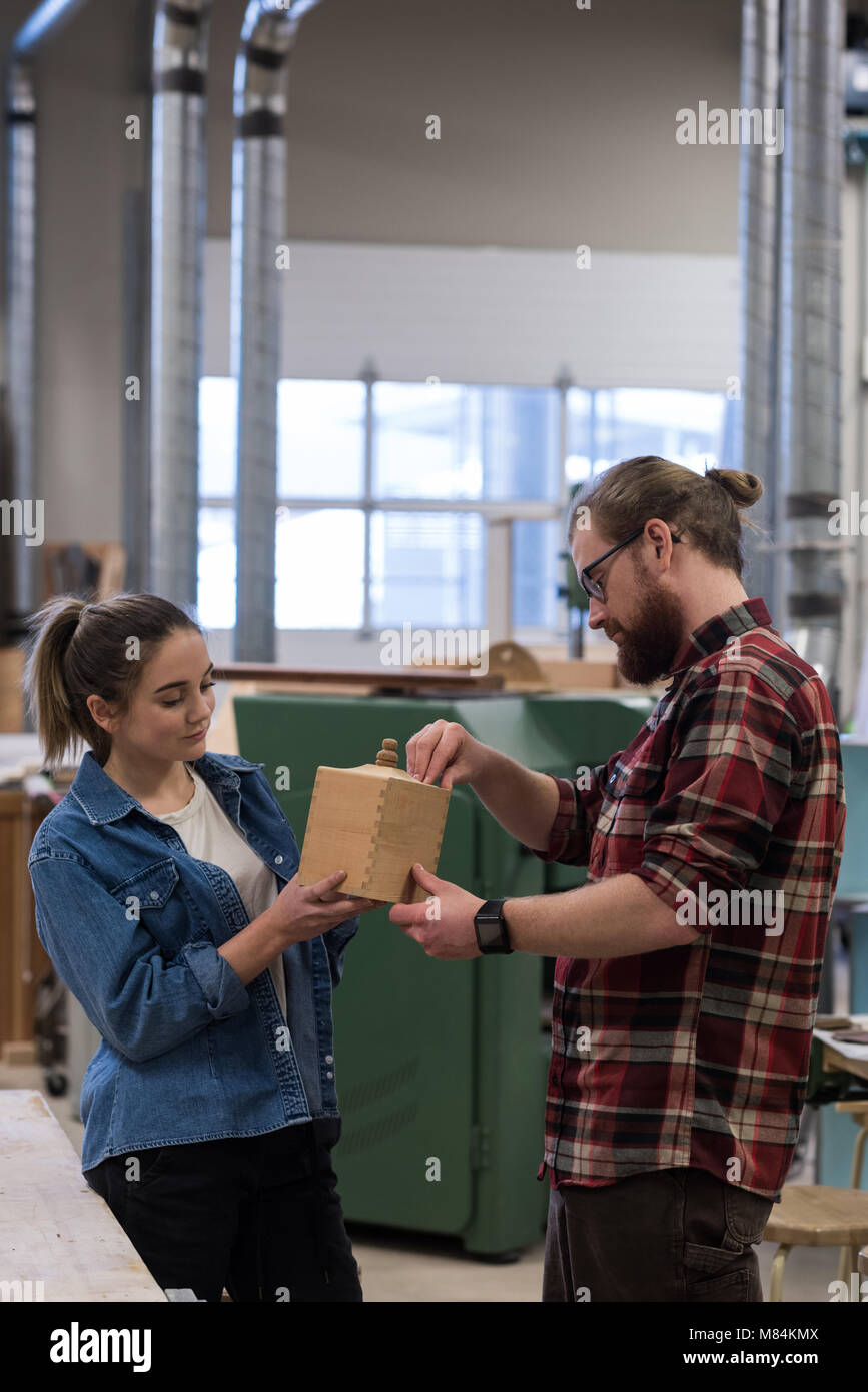 Maschio e femmina falegnami esaminando un pezzo di arredamento in legno Foto Stock