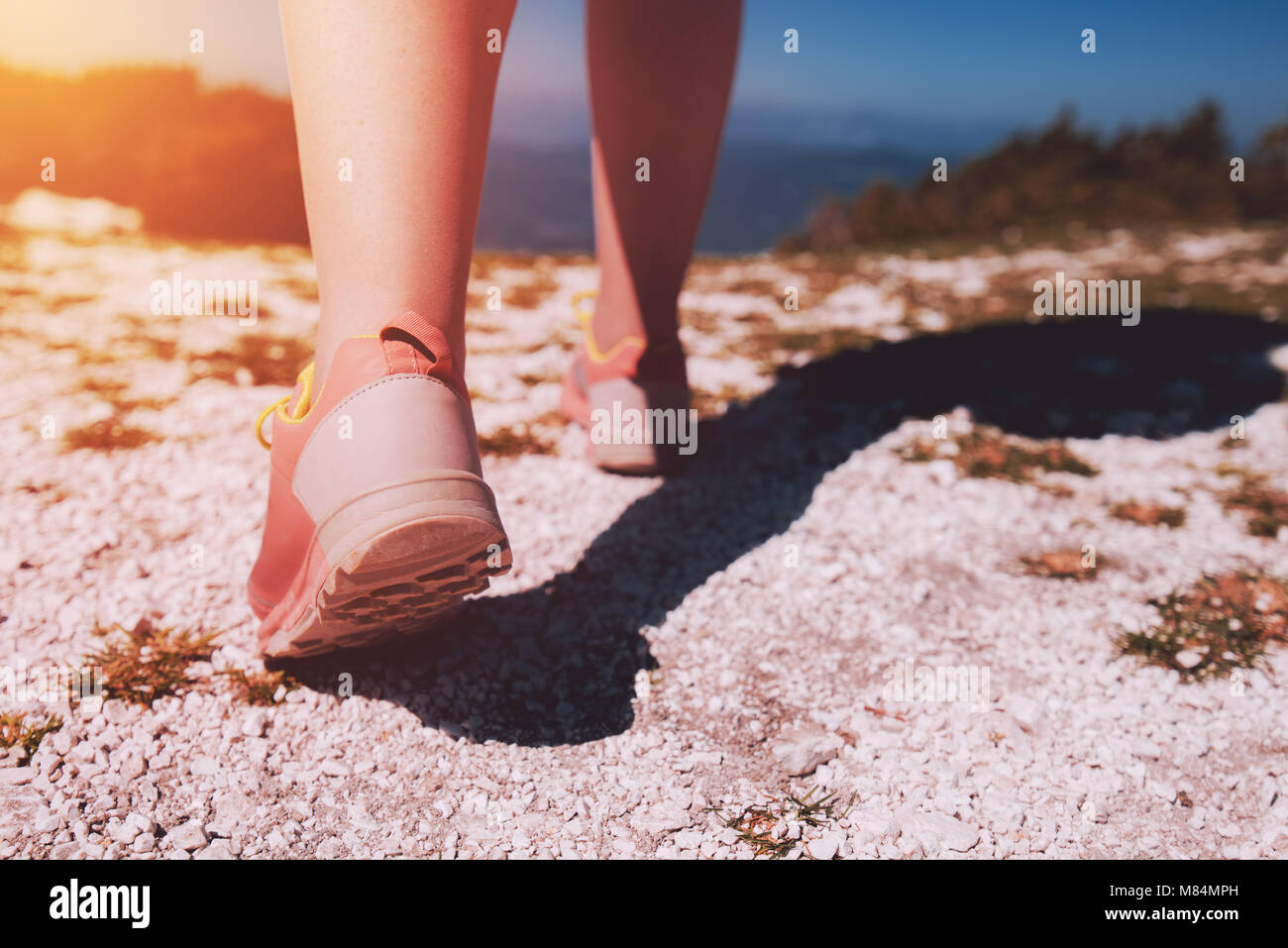 Atleta femminile escursionismo sul Monte percorso roccioso. Giovane donna con athletic sneakers jogging o in esecuzione in natura all'esterno. Uno stile di vita sano concetto tone Foto Stock