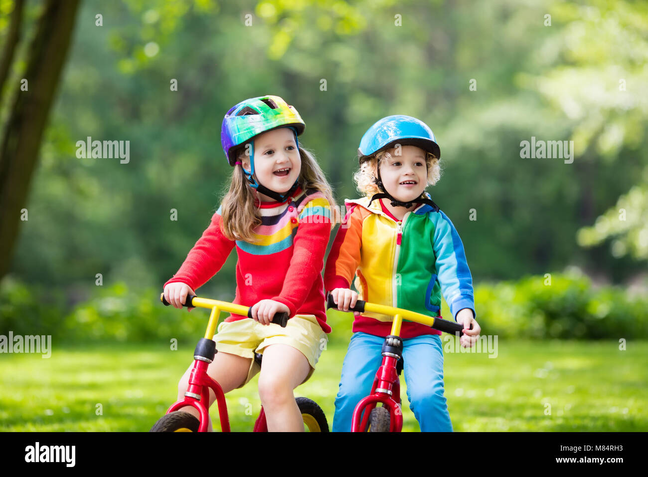 Bambini equilibrio di equitazione Bicicletta. Bambini in bicicletta nel parco di sole. Bambina e ragazzo ride glider bike su caldo giorno d'estate. Preschooler imparando a saldo Foto Stock