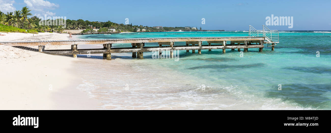 Un molo in legno sporge dalle acque turchesi dei Caraibi sulla spiaggia Spotts nella savana, Grand Cayman, Isole Cayman Foto Stock