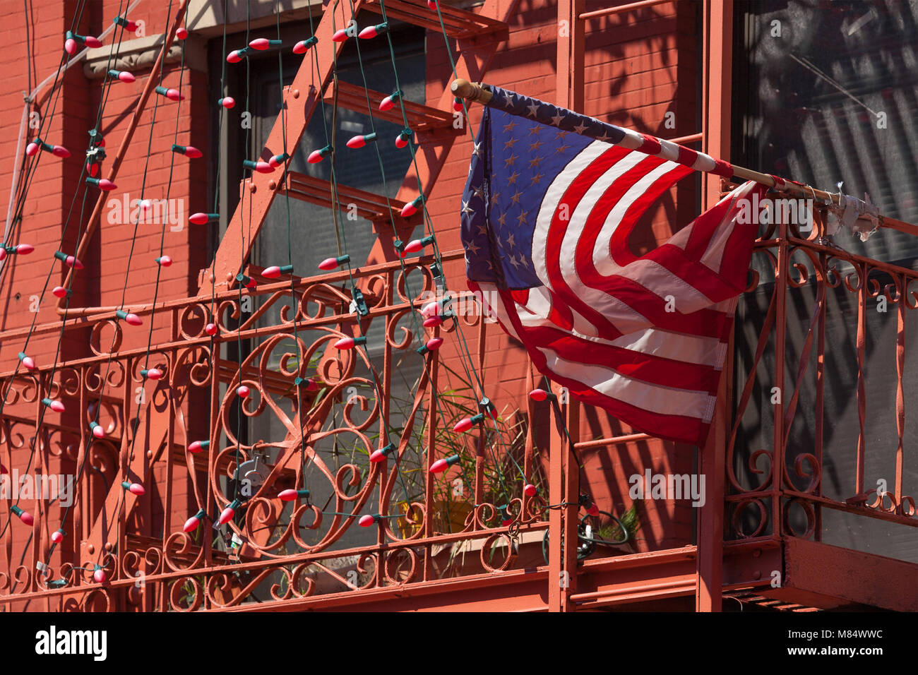 Bandiera americana attaccata alla parte anteriore di una casa tutta dipinta in rosso nella città di New York Foto Stock