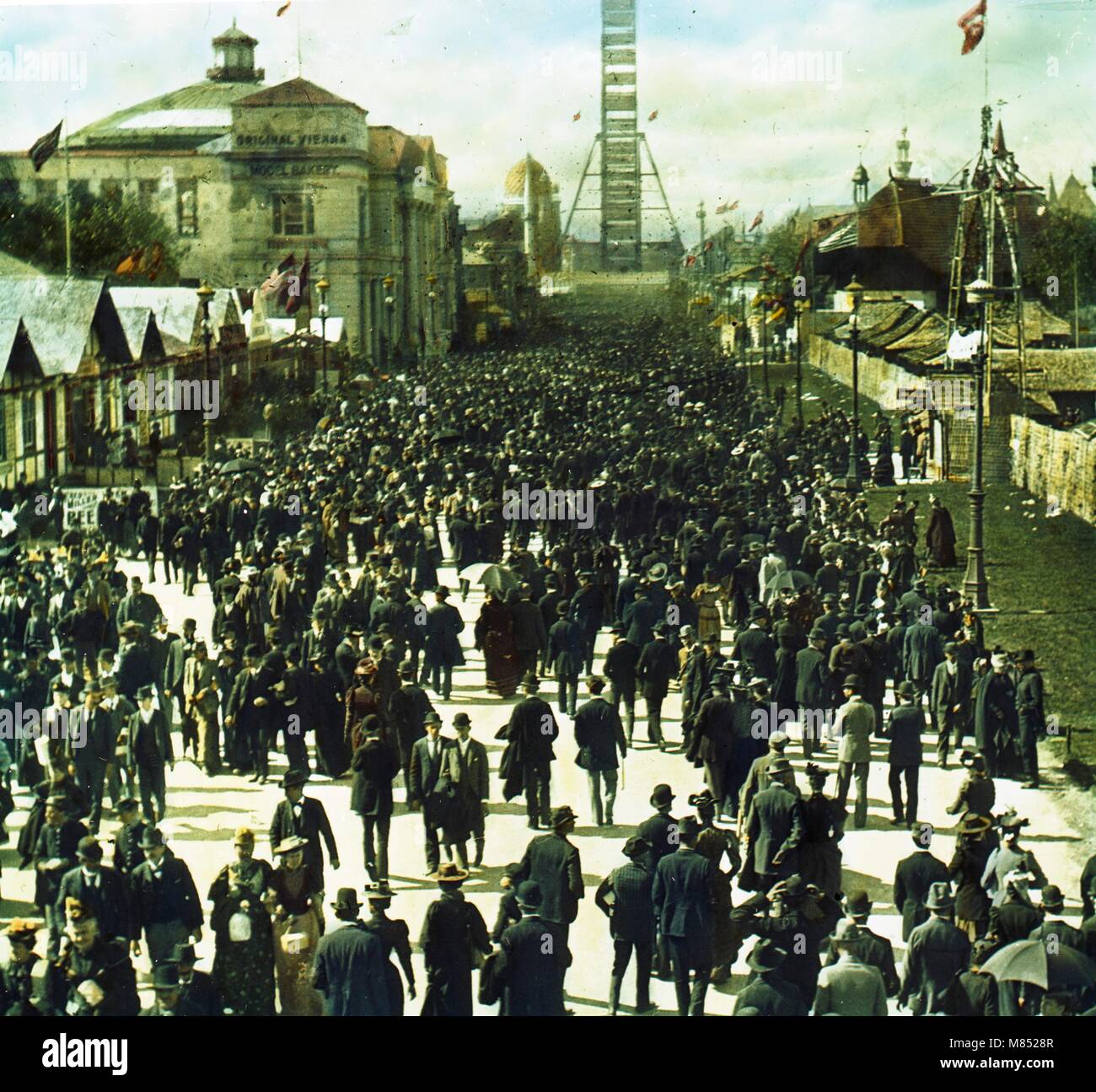 Vista colorata e ad alto angolo di folle di visitatori che esplorano i terreni della Louisiana Purchase Exposition, conosciuta anche come la St Louis World's Fair, St Louis, Missouri, 1904. La ruota panoramica, nota come ruota panoramica, è visibile in distanza. (Foto di Burton Holmes) Foto Stock