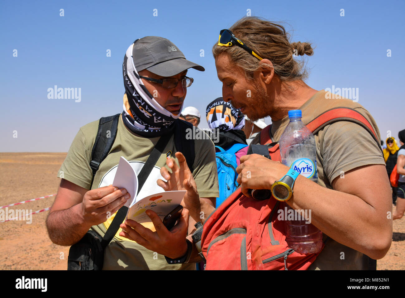 Due uomini parlare del libro nel deserto del Sahara Foto Stock