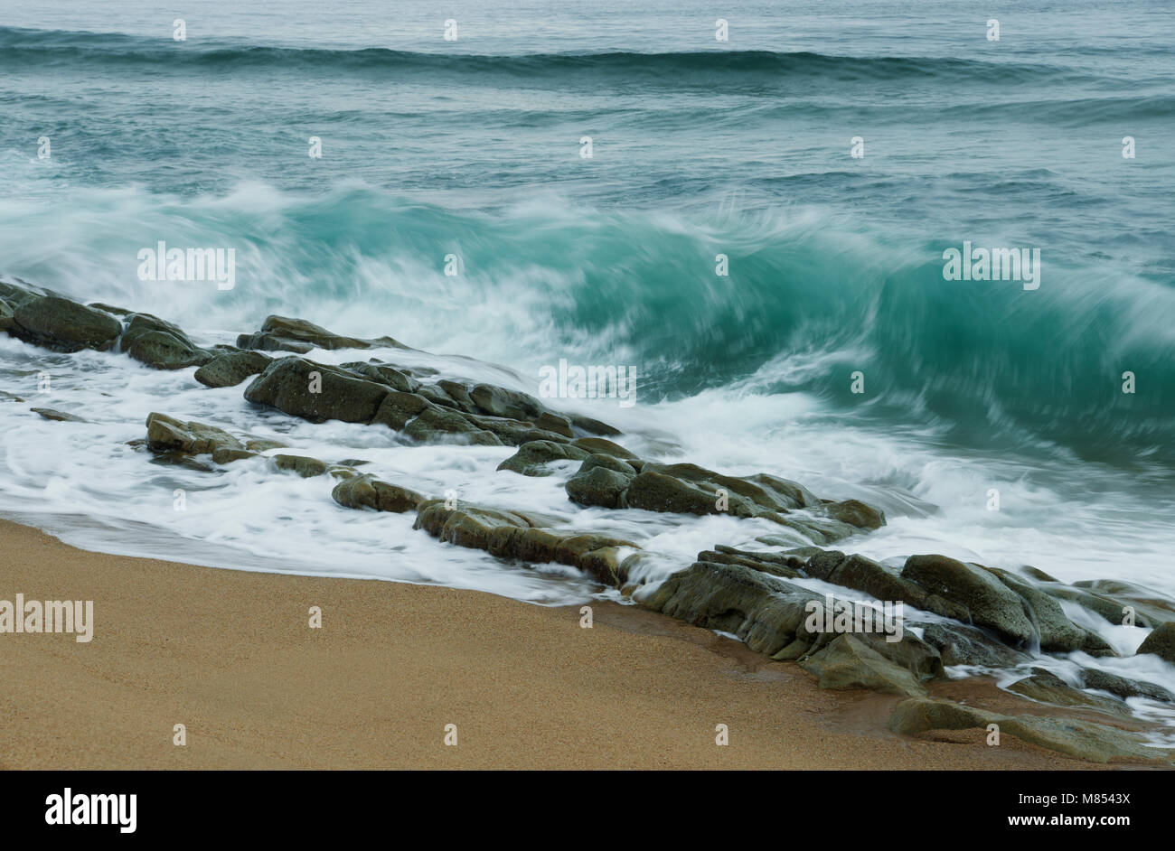 Durban, KwaZulu-Natal, Sud Africa, blur close up, delle onde che si infrangono sulla fila di lisce rocce umide, Umhlanga Rocks Beach Foto Stock
