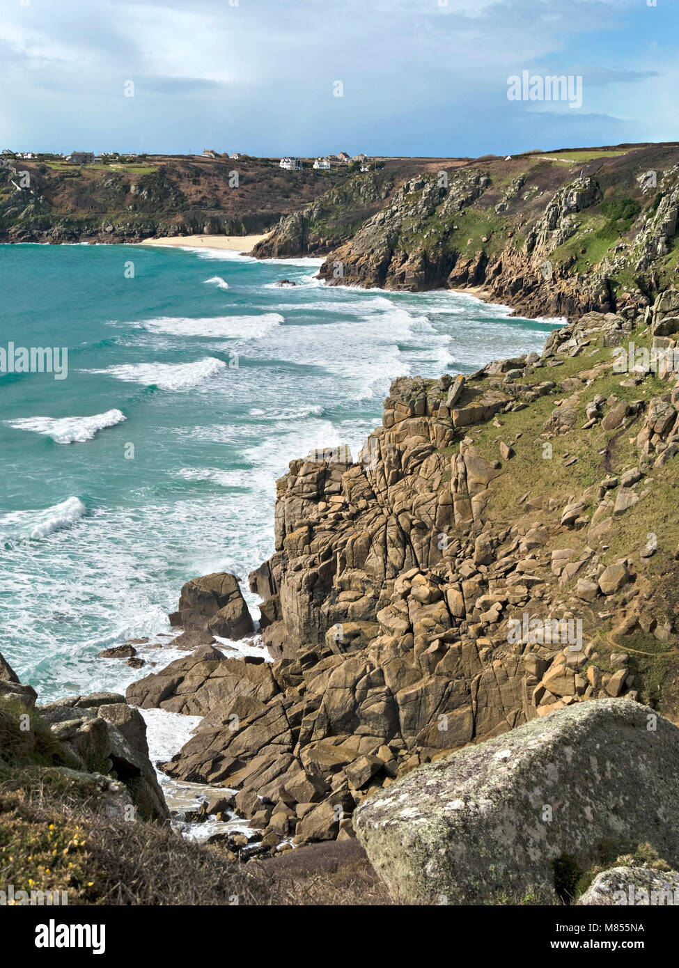 Onde, surf e rocciose scogliere del mare come visto dal sentiero costiero avvicinando Porthcurno beach in distanza, Cornwall, Regno Unito Foto Stock