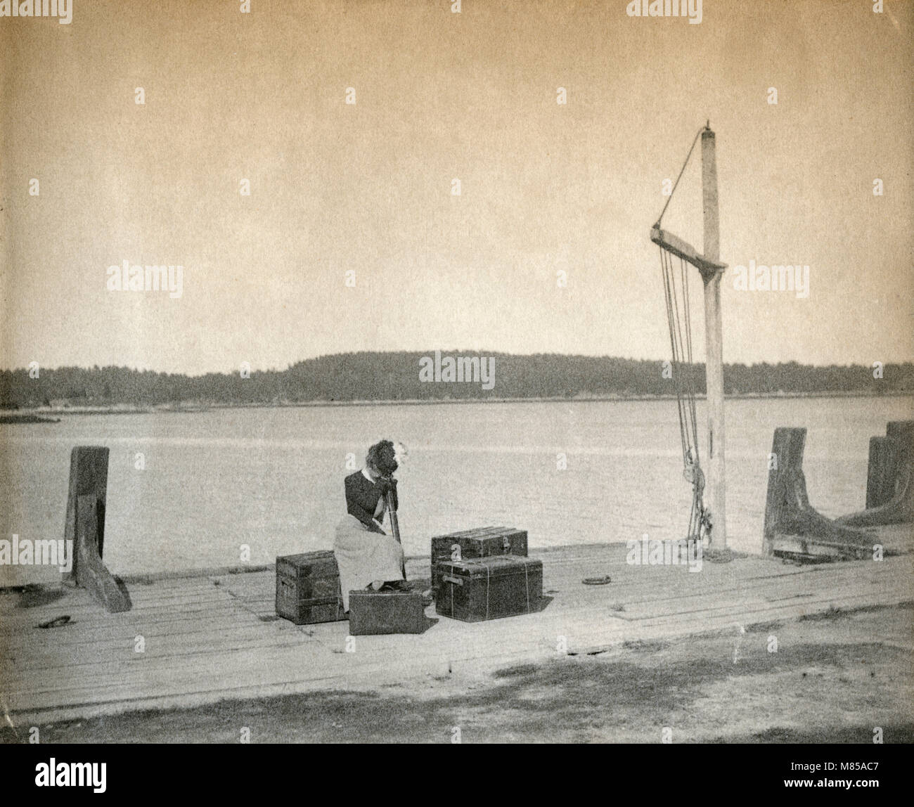 Antique circa 1905 fotografia, donna attende il traghetto sul dock sul fiume Sasanoa. La posizione è in o vicino a Riggsville (ora Robinhood), Maine in Sagadahoc County, Stati Uniti d'America. Foto Stock