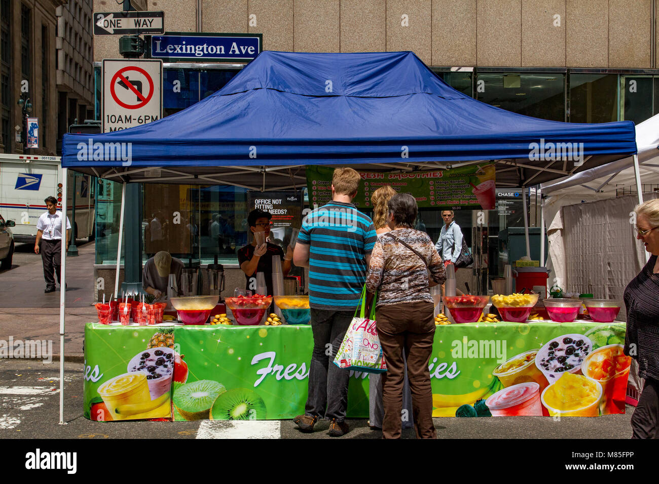 Persone che acquistano frullati di frutta fresca e drink presso un mercato in stallo sulla Lexington Avenue , Manhattan , New York Foto Stock